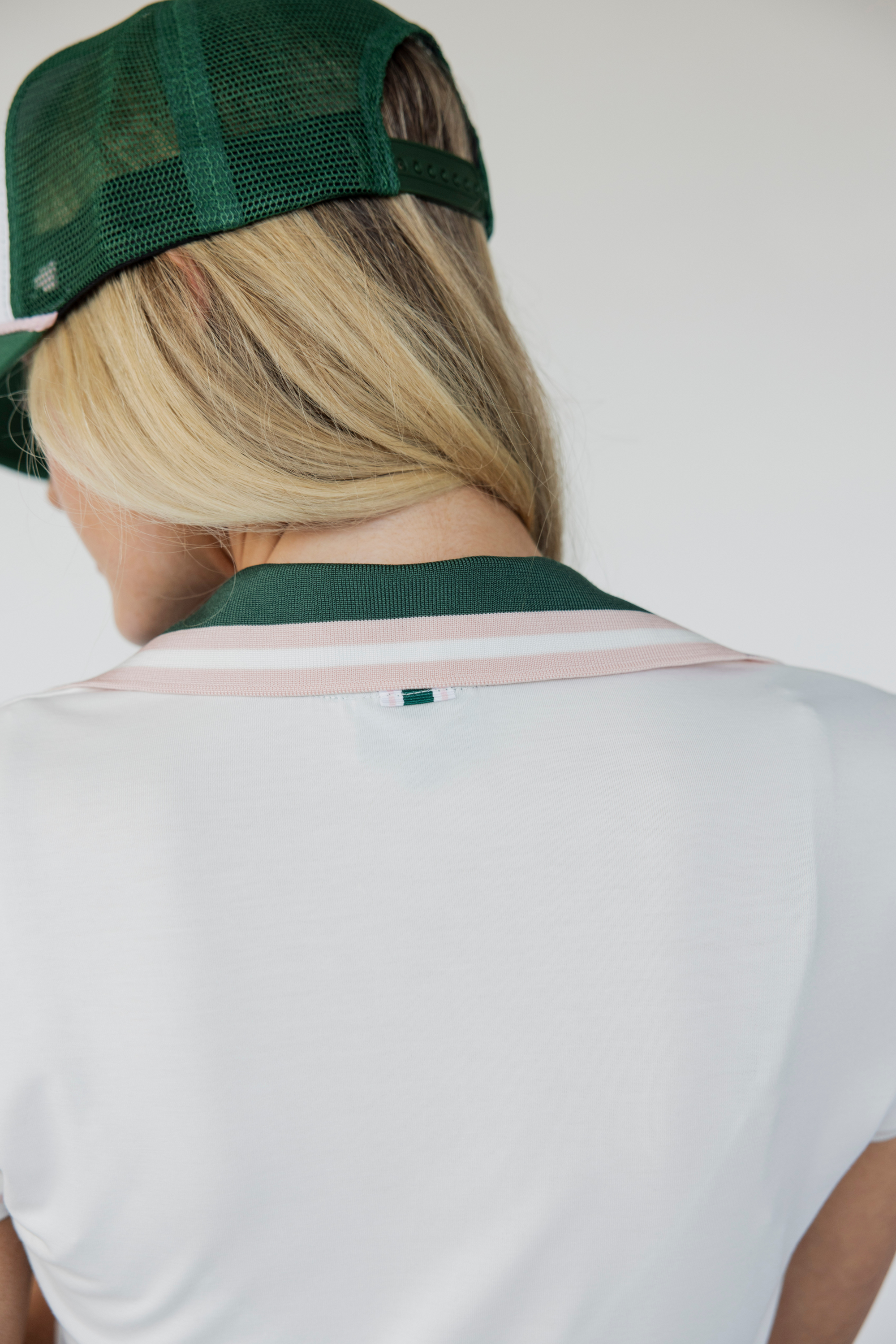 A women&#39;s golf polo named &quot;Angie Polo&quot; with capped sleeves and a retro preppy design. This fitted polo accentuates curves without being too tight, allowing for comfortable movement on the course. Perfect for a timeless, stylish look while playing golf