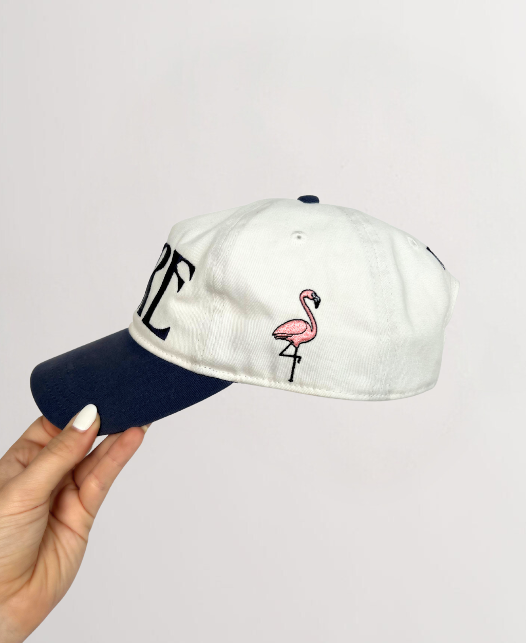 RT side view of white ball cap with indigo brim embroidered flamingo on side of ball cap