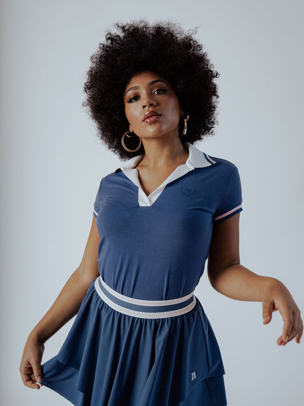 Blue Polo Shirt with white collar and form fitting and pink stripe on cap sleeve worn on a woman