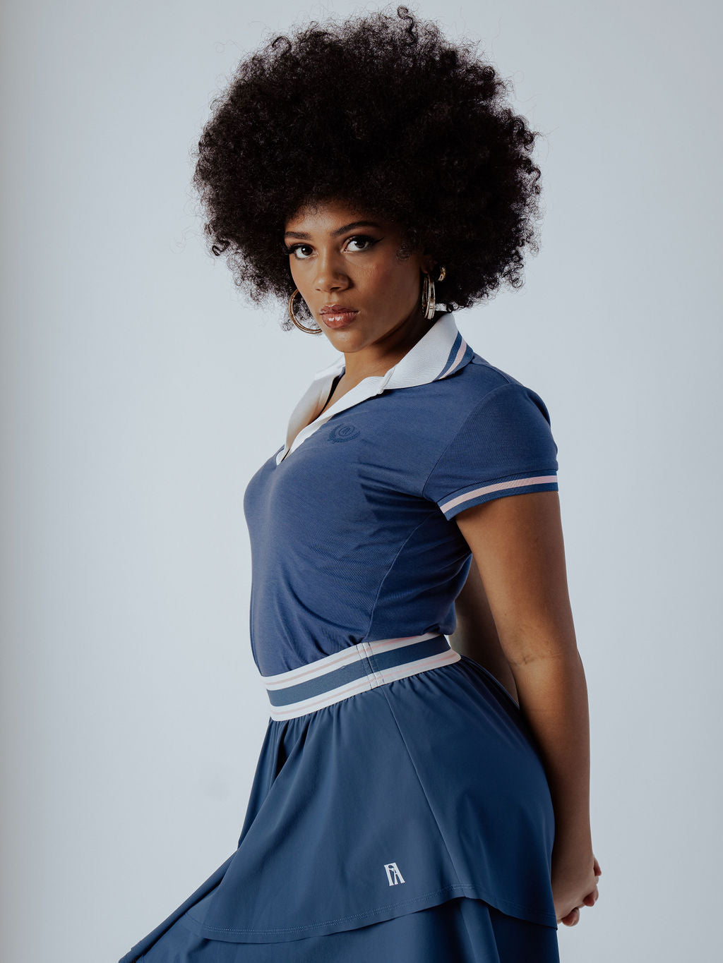 Blue Polo Shirt with white collar and form fitting and pink stripe on cap sleeve worn on a woman