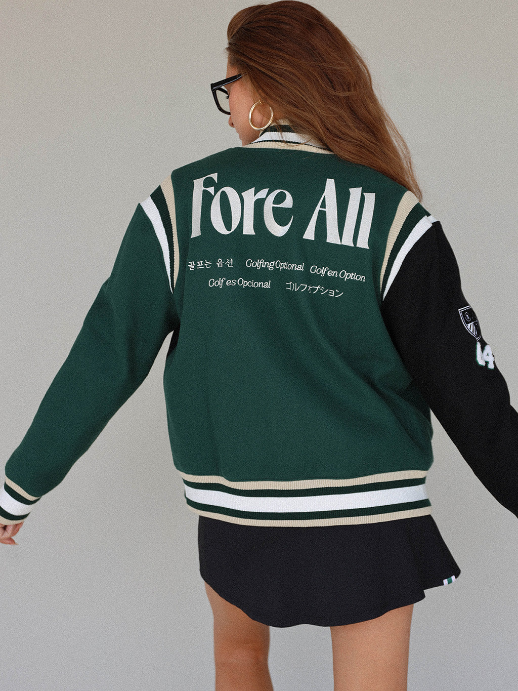 Close-up of the 'Captain's Jacket' from the Royal Collection, showcasing its autumn-inspired hues. Features include exclusive capsule patches, color blocking, black/green checkered lining, and 'Fore All' embroidery on the back. This vintage-inspired varsity jacket combines classic style with modern details, ideal for making a statement in your fall wardrobe.