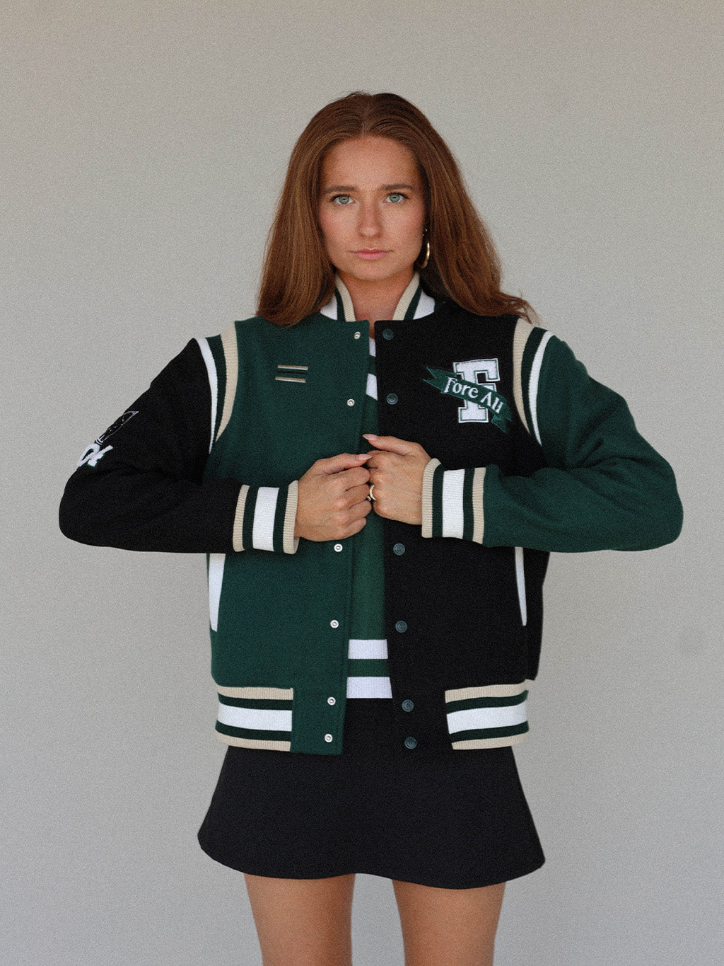 Close-up of the &#39;Captain&#39;s Jacket&#39; from the Royal Collection, showcasing its autumn-inspired hues. Features include exclusive capsule patches, color blocking, black/green checkered lining, and &#39;Fore All&#39; embroidery on the back. This vintage-inspired varsity jacket combines classic style with modern details, ideal for making a statement in your fall wardrobe.