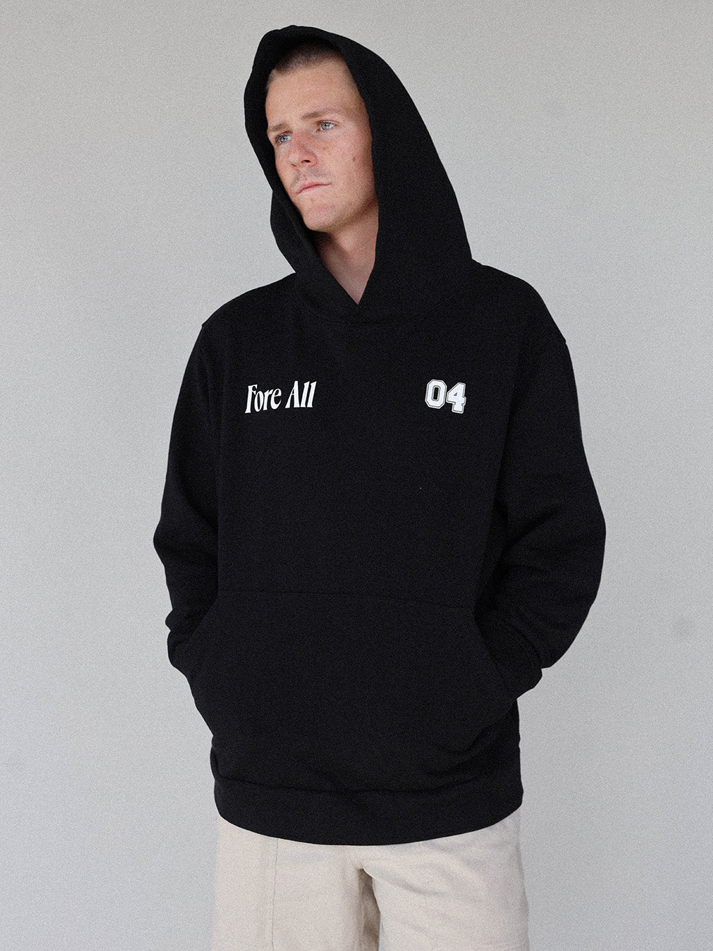 "Close-up of the 'Global Hoodie' from the Royal Collection, inspired by autumn hues. This cozy, slightly oversized hoodie features a substantial pocket for golf and personal items and a full-coverage hood. 'Fore All' details on the front and back include the classic 'Golfing Optional' phrase in five languages. Perfect for combining comfort and global style this season."