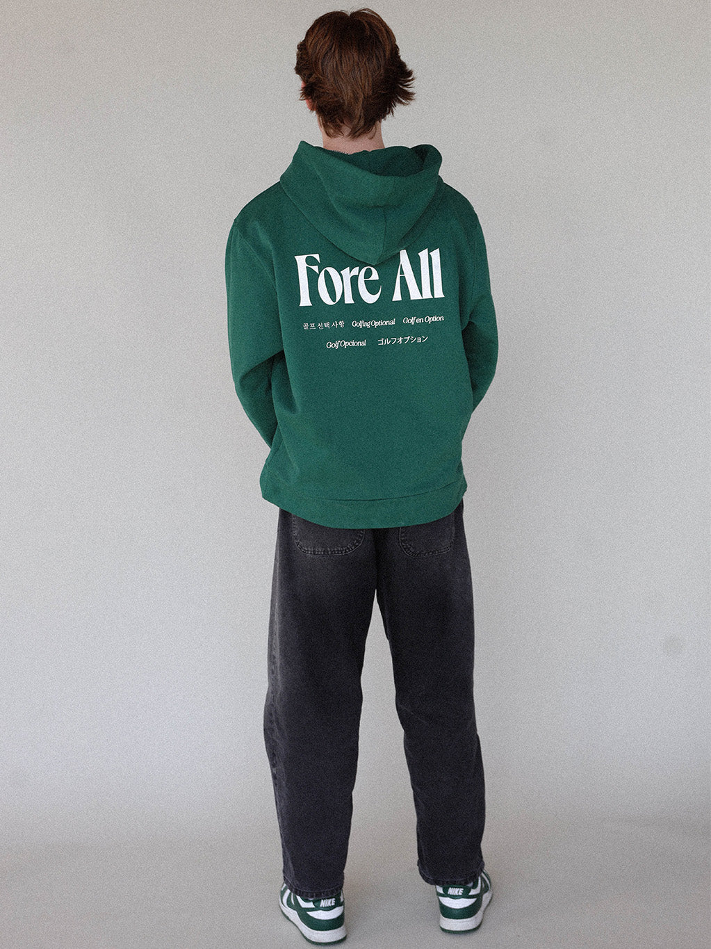 "Close-up of the 'Global Hoodie' from the Royal Collection, inspired by autumn hues. This cozy, slightly oversized hoodie features a substantial pocket for golf and personal items and a full-coverage hood. 'Fore All' details on the front and back include the classic 'Golfing Optional' phrase in five languages. Perfect for combining comfort and global style this season."