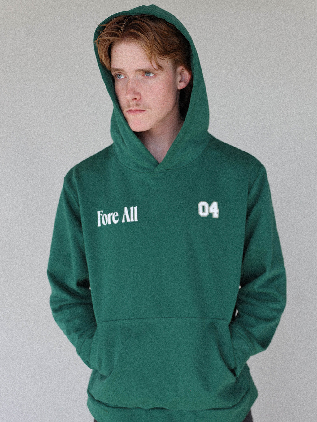 "Close-up of the 'Global Hoodie' from the Royal Collection, inspired by autumn hues. This cozy, slightly oversized hoodie features a substantial pocket for golf and personal items and a full-coverage hood. 'Fore All' details on the front and back include the classic 'Golfing Optional' phrase in five languages. Perfect for combining comfort and global style this season."