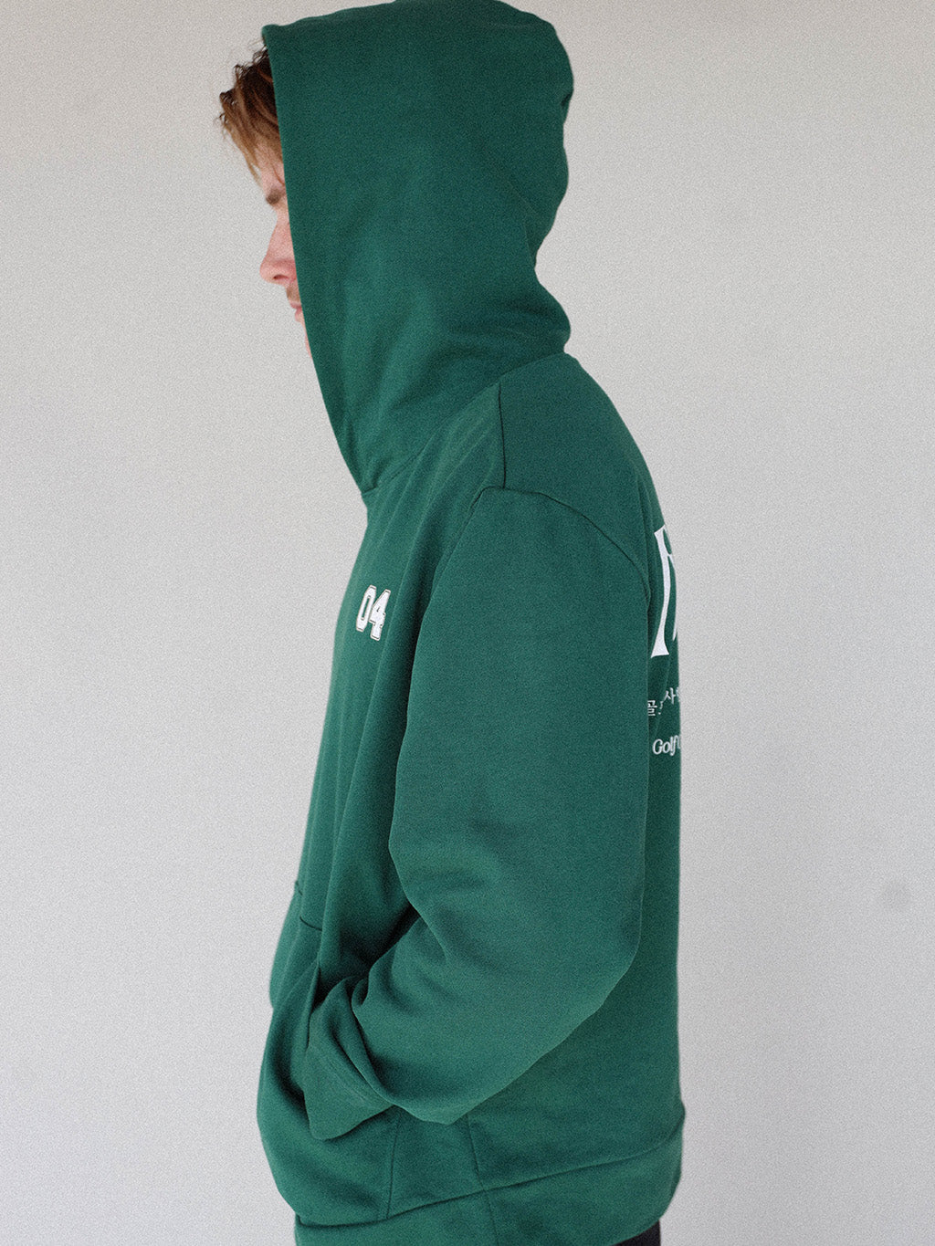 &quot;Close-up of the &#39;Global Hoodie&#39; from the Royal Collection, inspired by autumn hues. This cozy, slightly oversized hoodie features a substantial pocket for golf and personal items and a full-coverage hood. &#39;Fore All&#39; details on the front and back include the classic &#39;Golfing Optional&#39; phrase in five languages. Perfect for combining comfort and global style this season.&quot;