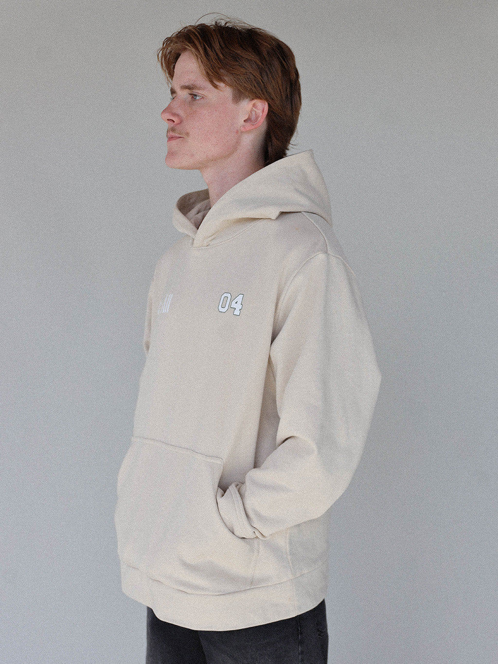 "Close-up of the 'Global Hoodie' from the Royal Collection, inspired by autumn hues. This cozy, slightly oversized hoodie features a substantial pocket for golf and personal items and a full-coverage hood. 'Fore All' details on the front and back include the classic 'Golfing Optional' phrase in five languages. Perfect for combining comfort and global style this season."