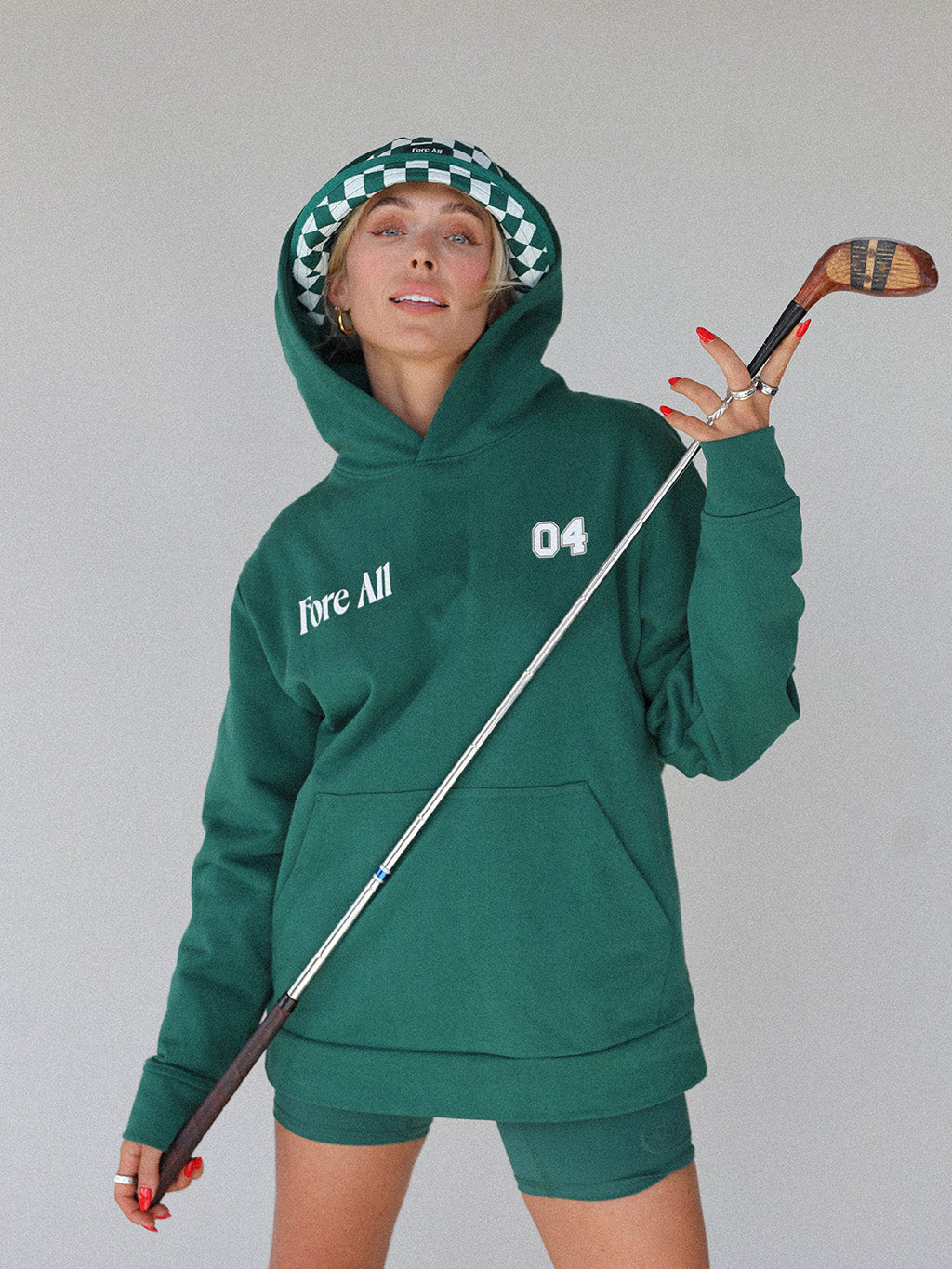  &quot;Close-up of the &#39;Global Hoodie&#39; from the Royal Collection, inspired by autumn hues. This cozy, slightly oversized hoodie features a substantial pocket for golf and personal items and a full-coverage hood. &#39;Fore All&#39; details on the front and back include the classic &#39;Golfing Optional&#39; phrase in five languages. Perfect for combining comfort and global style this season.&quot;