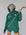  "Close-up of the 'Global Hoodie' from the Royal Collection, inspired by autumn hues. This cozy, slightly oversized hoodie features a substantial pocket for golf and personal items and a full-coverage hood. 'Fore All' details on the front and back include the classic 'Golfing Optional' phrase in five languages. Perfect for combining comfort and global style this season."